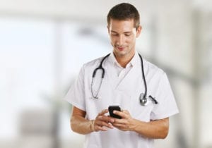 Young doctor man with stethoscope sending message in the hospital.